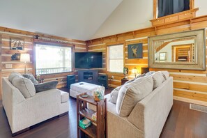 Un salon chaleureux avec deux canapés, un téléviseur, des murs en bois et un grand miroir.