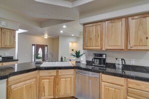 A modern kitchen with wooden cabinets, a granite countertop, stainless steel appliances, and a built-in dishwasher.