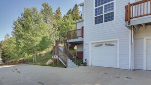 Une maison à deux étages avec un escalier en bois menant à un balcon, un garage et une allée.