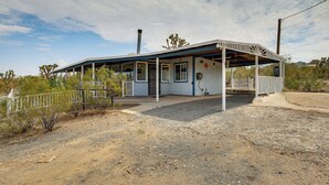 A single-story building with a covered porch, a chimney, and a fenced yard. - 'Abigail's Ranch' - Dog-Friendly Dolan Springs Gem (Dolan Springs)