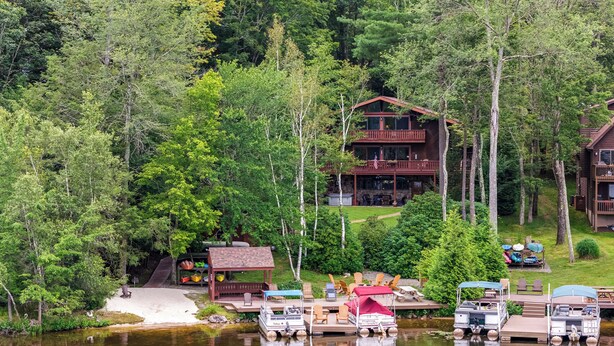 A lakeside lodge with a dock, boats, and outdoor seating. - Beech Mt Lakefront Gem! Hot Tub, Kayaks, Billiards (Beech Mountain Lakes)