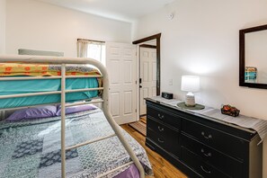 Een slaapkamer met een stapelbed, een dressoir, een spiegel en een deur.