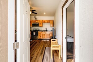 A narrow hallway leading to a kitchen with wooden cabinets, a microwave, and a ceiling fan. - < 2 Mi to Dtwn: Pet-Friendly Getaway in Fairbanks (Fairbanks)