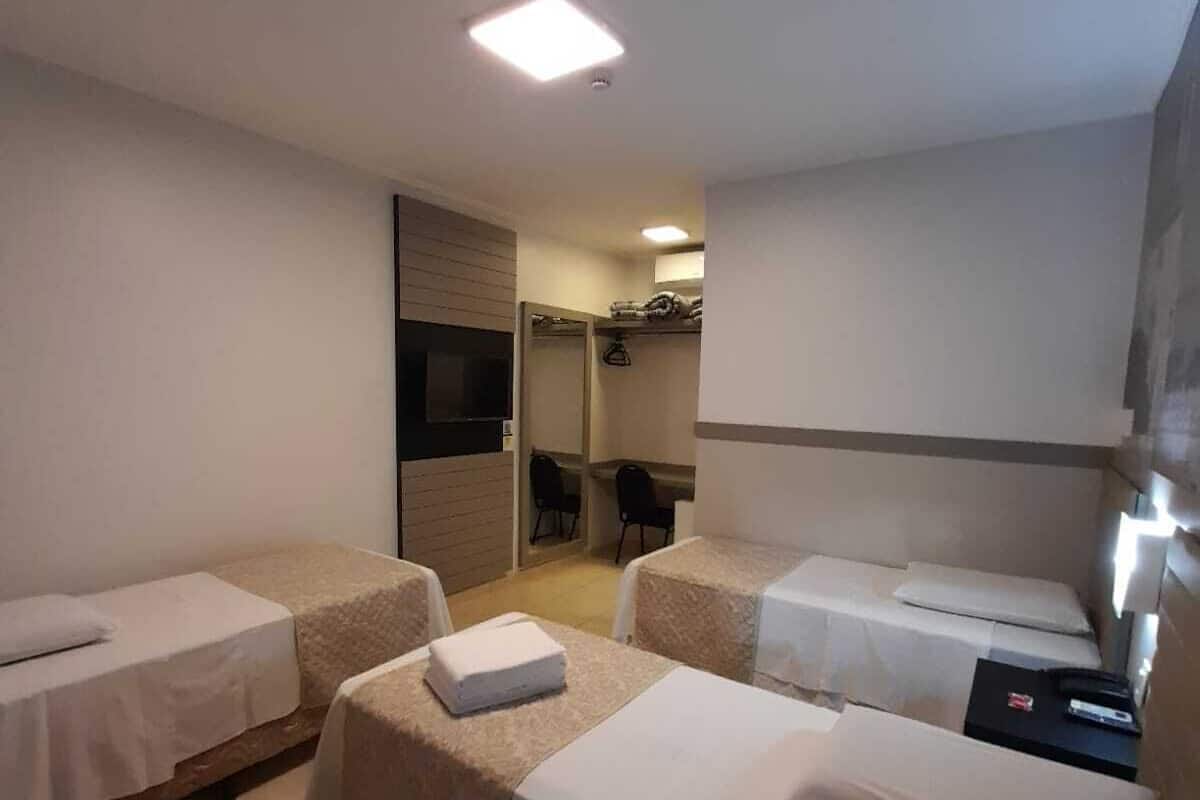 Hotellihuone, jossa on kaksi erillistä sänkyä, pieni työpöytä, tuoli ja televisio.
