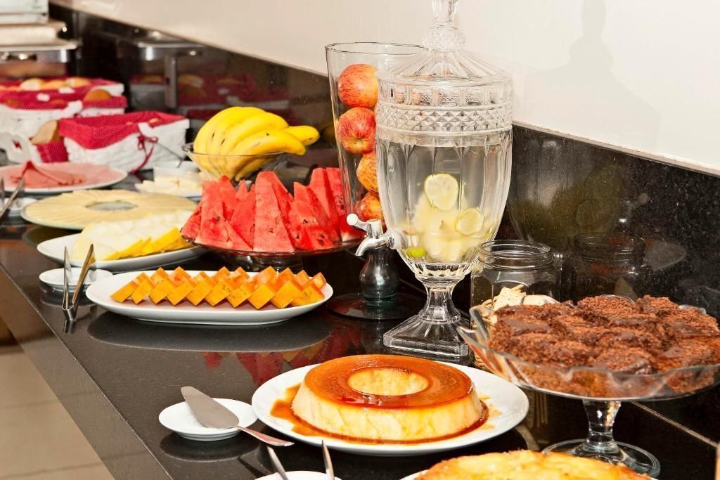 Un buffet proposant divers plats, notamment des fruits, un verre d’eau et des desserts.