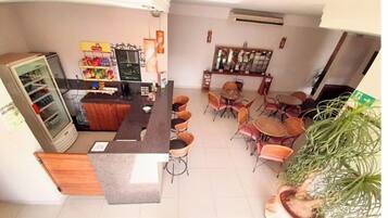 Cafetería con mostrador, sillas, refrigerador y una planta.