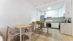 A modern kitchen with white cabinets, a wooden dining table, and two chairs.
