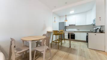 Une cuisine moderne avec des meubles blancs, une table à manger en bois et deux chaises.