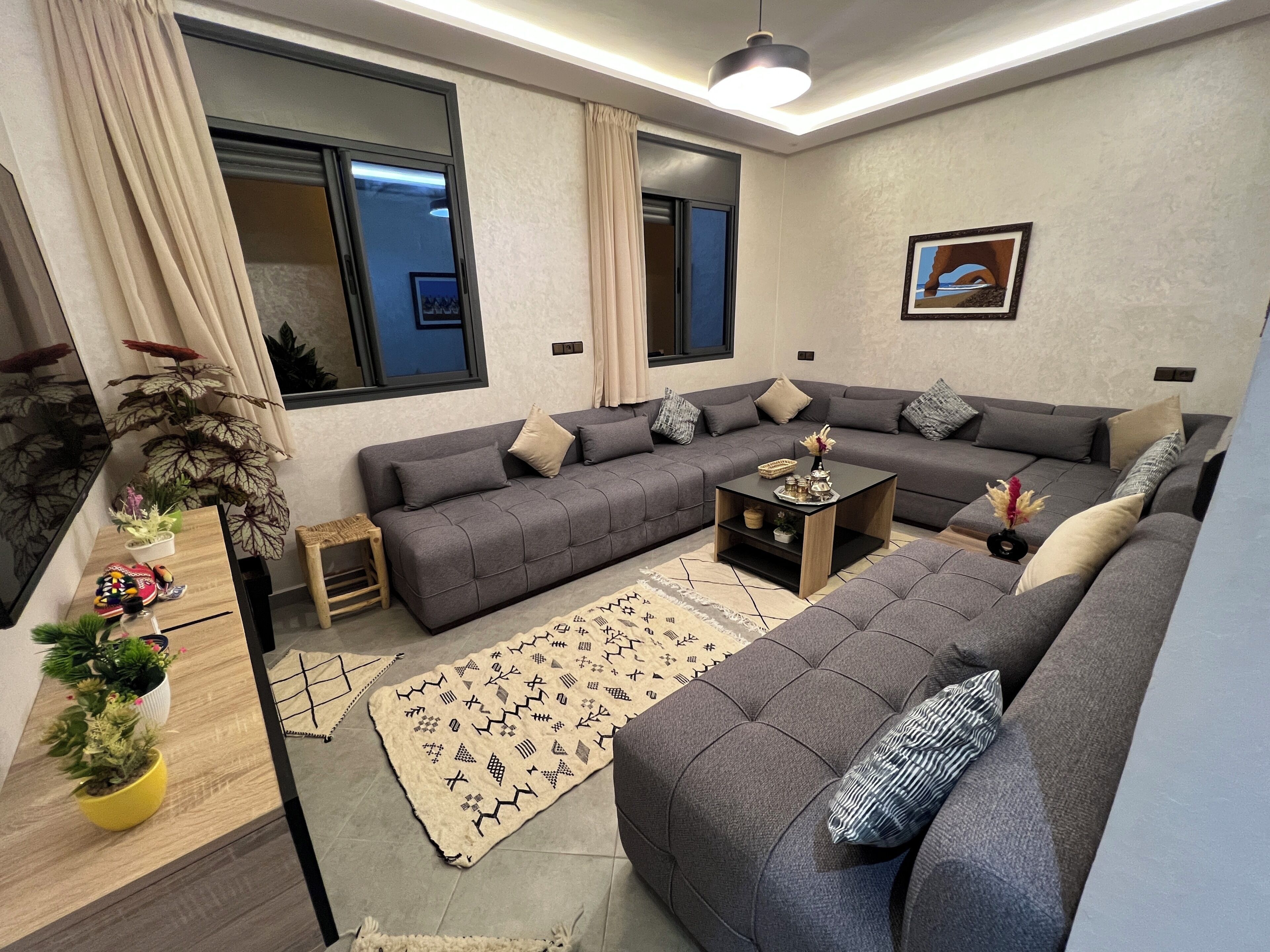 A modern living room with a grey sofa, a small wooden coffee table, and a patterned rug.