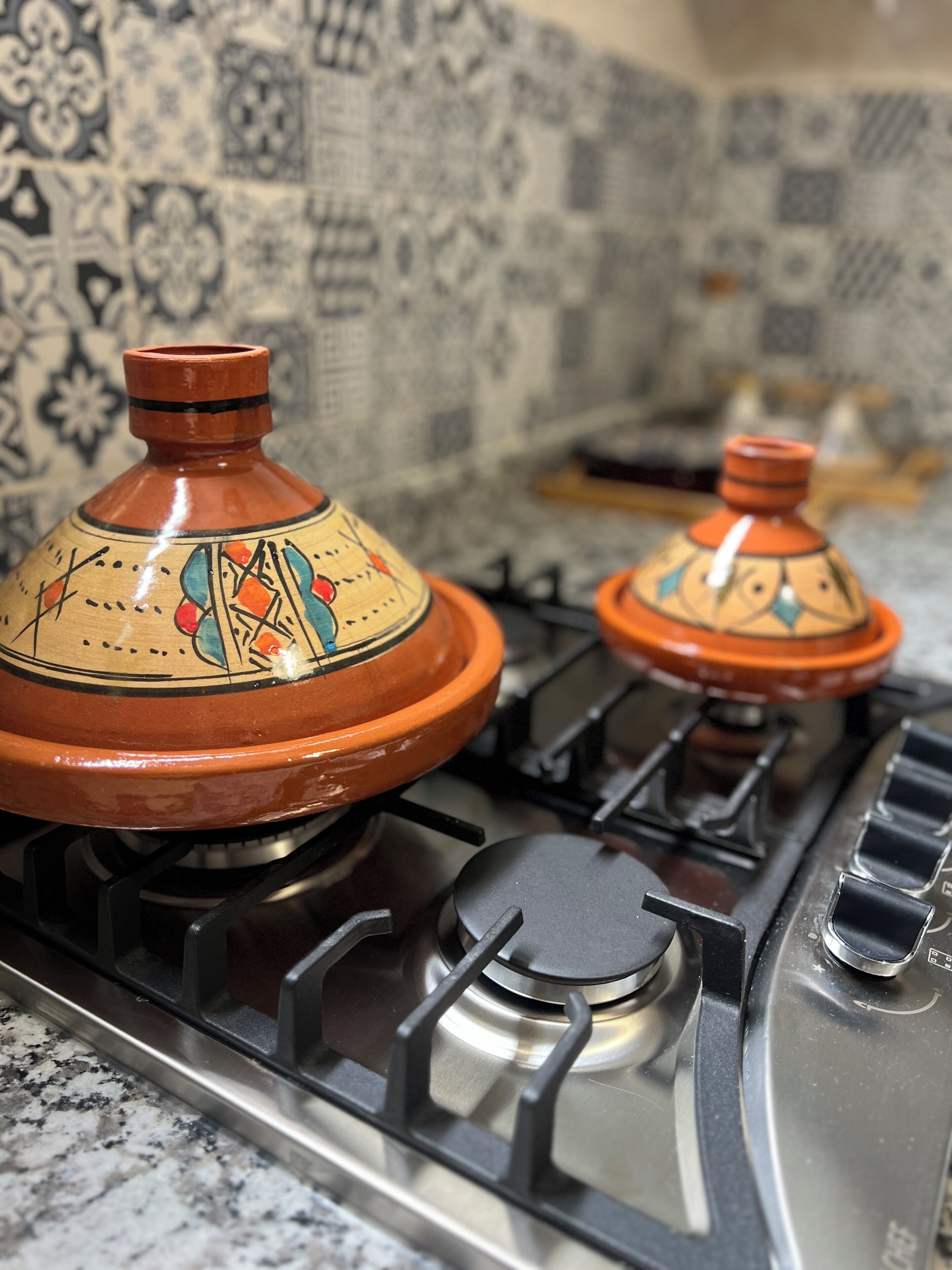 A kitchen with two traditional Moroccan tagines on a gas stove.