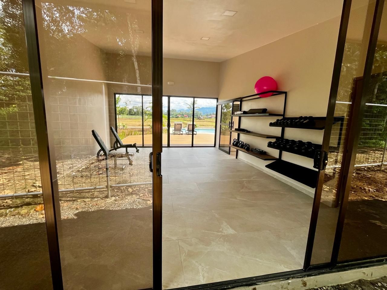 A room with a sliding glass door leading to an outdoor area, a bench, and a shelf with items.