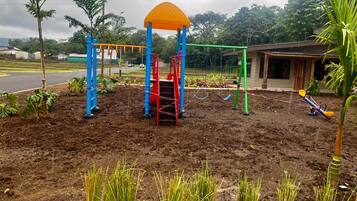 Un parque infantil con un área de escalada, columpios y un balancín.