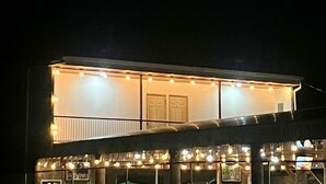 A modern building with a balcony and string lights. - Luisito steak house & hotel (La Fortuna)