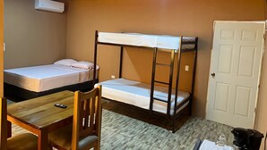 A small, cozy room with two bunk beds, a wooden desk, a chair, and a white door. - Luisito steak house & hotel (La Fortuna)