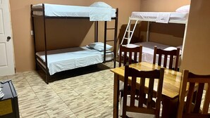 A bunk bed room with a wooden table and chairs, a ladder, and an air conditioning unit. - Luisito steak house & hotel (La Fortuna)