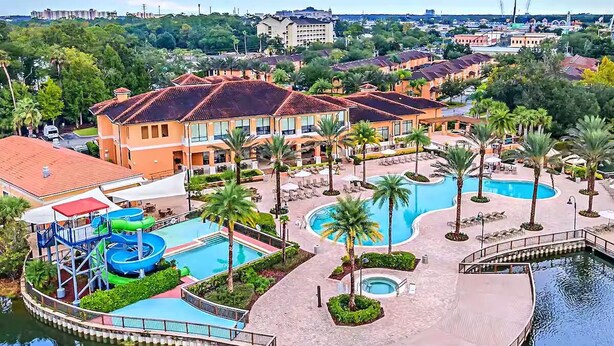 A resort with multiple swimming pools, palm trees, and a water slide. - Disney Escape: Pool + Slides + Resort Vibes! (Kissimmee)