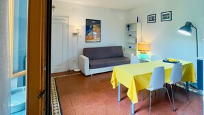 A small, well-lit room with a sofa, a dining table with chairs, a lamp, and a framed picture on the wall. - Apartment with balcony in historic building, 100m from the Arena (Verona)