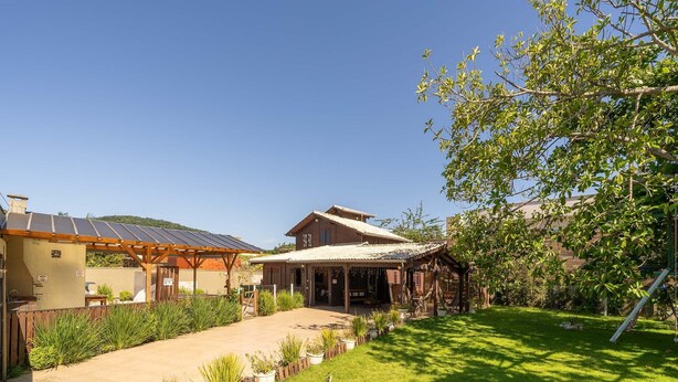 Una casa con porche cubierto, patio cercado y jardín con plantas en macetas.