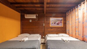 Una habitación con dos camas, techo de madera, unidad de aire acondicionado, una mesita y un cuadro en la pared.
