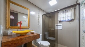 Un baño con un lavamanos amarillo, un inodoro blanco y una ducha con cerramiento de vidrio.