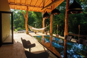 Un espace piscine extérieur paisible, agrémenté d’un hamac, de sièges et d’une pergola en bois.