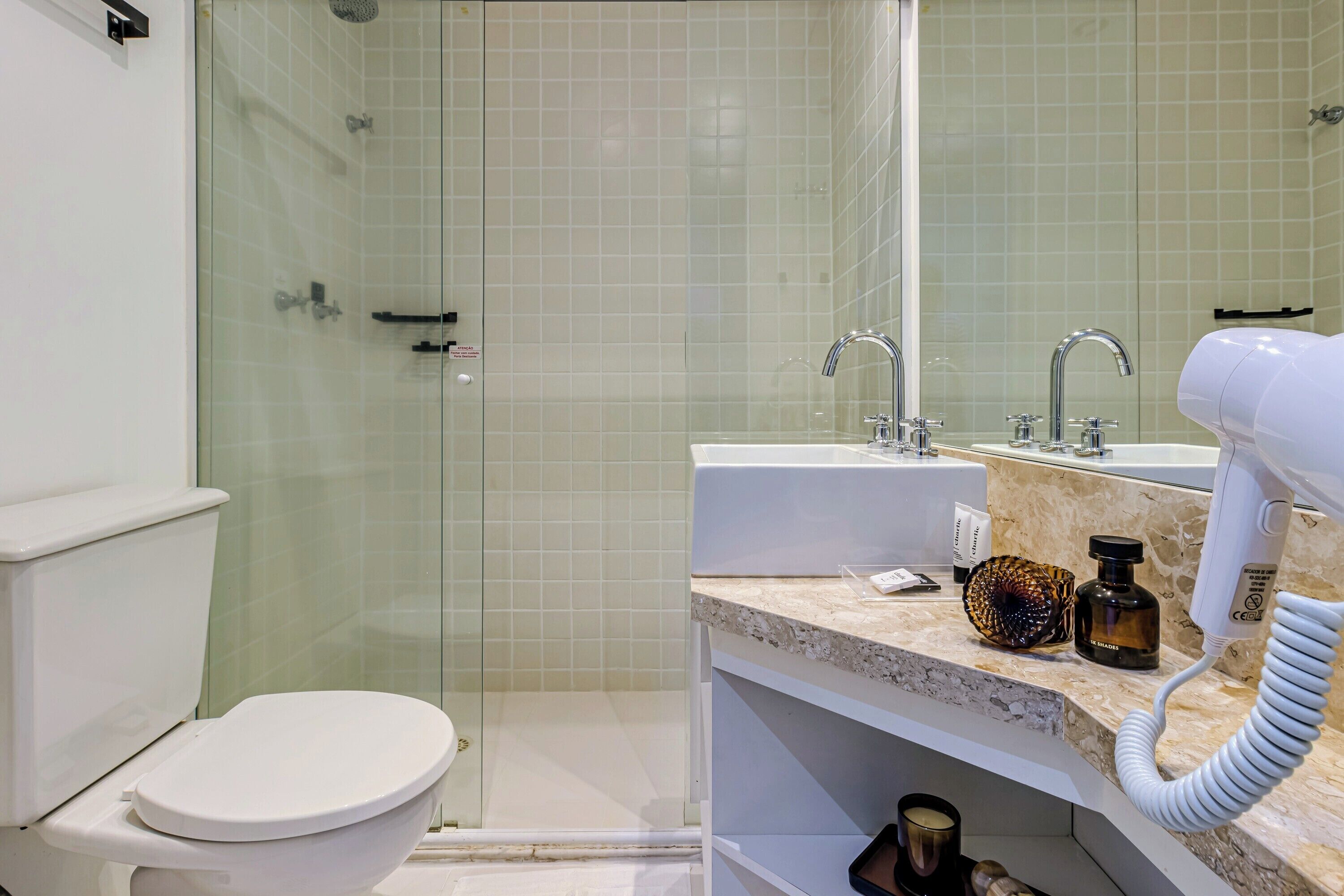 Un baño con inodoro, ducha, lavabo y secador de pelo en el mostrador.