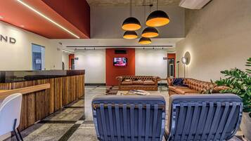 A modern lobby with a reception desk, seating area, and a television screen.