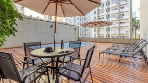 A rooftop terrace with a pool, lounge chairs, and a table with chairs. - Charlie Poeta Drummond Jardins (São Paulo)