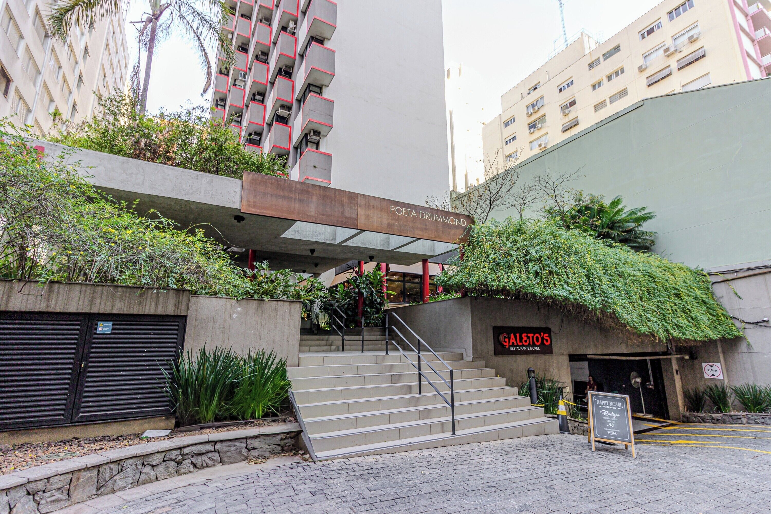A building with a staircase leading to a restaurant named "GALETO'S" and a sign for "POETA DRUMMOND" above the entrance.
