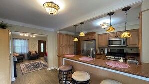Een moderne keuken met houten kastjes, roestvrijstalen apparatuur en hangende verlichting.