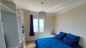 Un dormitorio con una cama grande, un armario, una mesita de noche y una ventana con vistas.