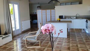 Una cocina moderna con una isla central, un comedor con una silla y vista al salón.