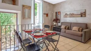 A dining area with a table set for four, a sofa, and a cityscape painting on the wall. - Le Capouane - The Tower of Augustus (La Turbie)