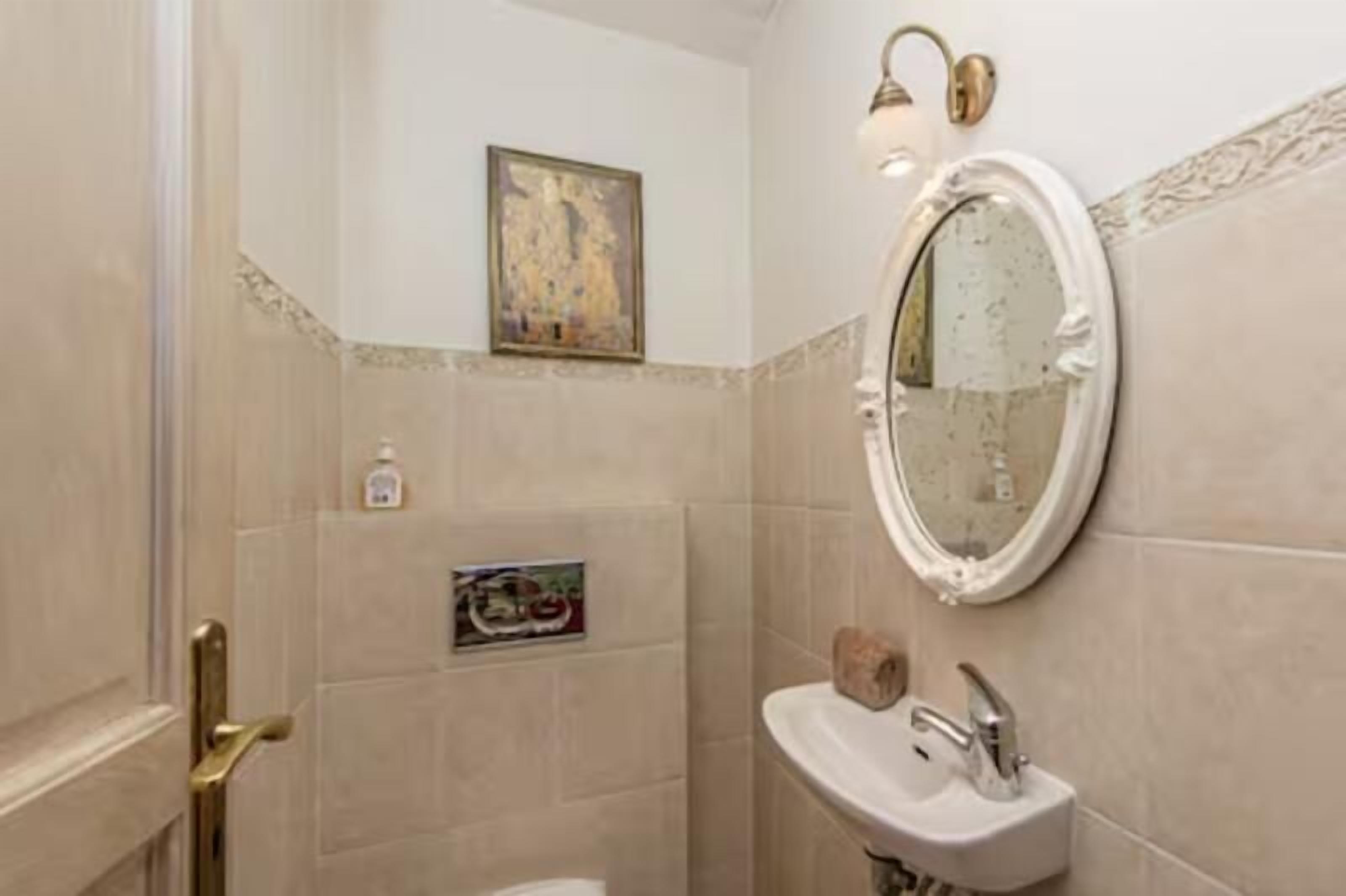 Une salle de bain avec un miroir rond, un lavabo et une porte.
