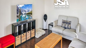 Un salon moderne avec un téléviseur, un canapé et une table basse.