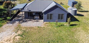 Une maison moderne avec un toit en pente, un patio couvert et un petit jardin.