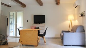 Una sala de estar con una mesa de madera, un sofá gris, un televisor y una lámpara.