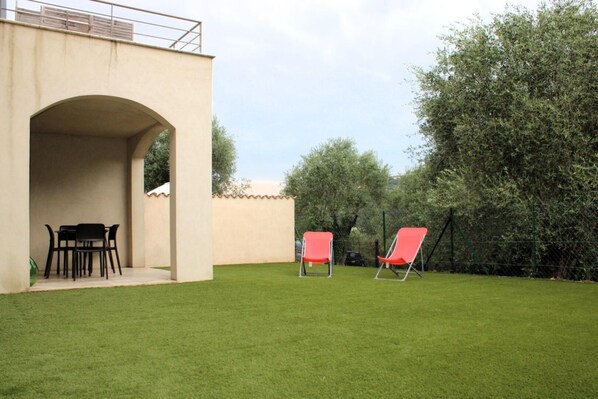 A patio area with a table and chairs, a covered seating area, and a well-maintained lawn.
