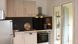Una cocina compacta con horno integrado, microondas y estufa.