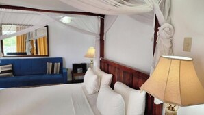 Un dormitorio con cama con dosel, un sofá azul y una lámpara.