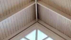 Una habitación con techos altos, vigas de madera y un tragaluz.
