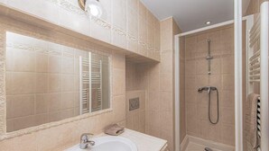 A bathroom with a large sink, a mirror, a shower, and beige tiles. - Le Du Guet - Augustus Tower (La Turbie)