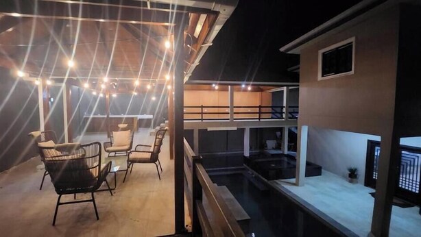 Terraza en la azotea con mobiliario exterior e iluminación con luces colgantes.