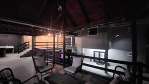 Un espacio interior amplio con techo alto, varios conjuntos de asientos y una escalera que sube a un nivel superior.