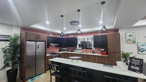 Una cocina moderna con una isla central, electrodomésticos de acero inoxidable e iluminación colgante.