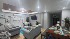 Una sala de estar moderna con un sofá, una mesa de centro y un comedor con mesa dispuesta para cuatro.