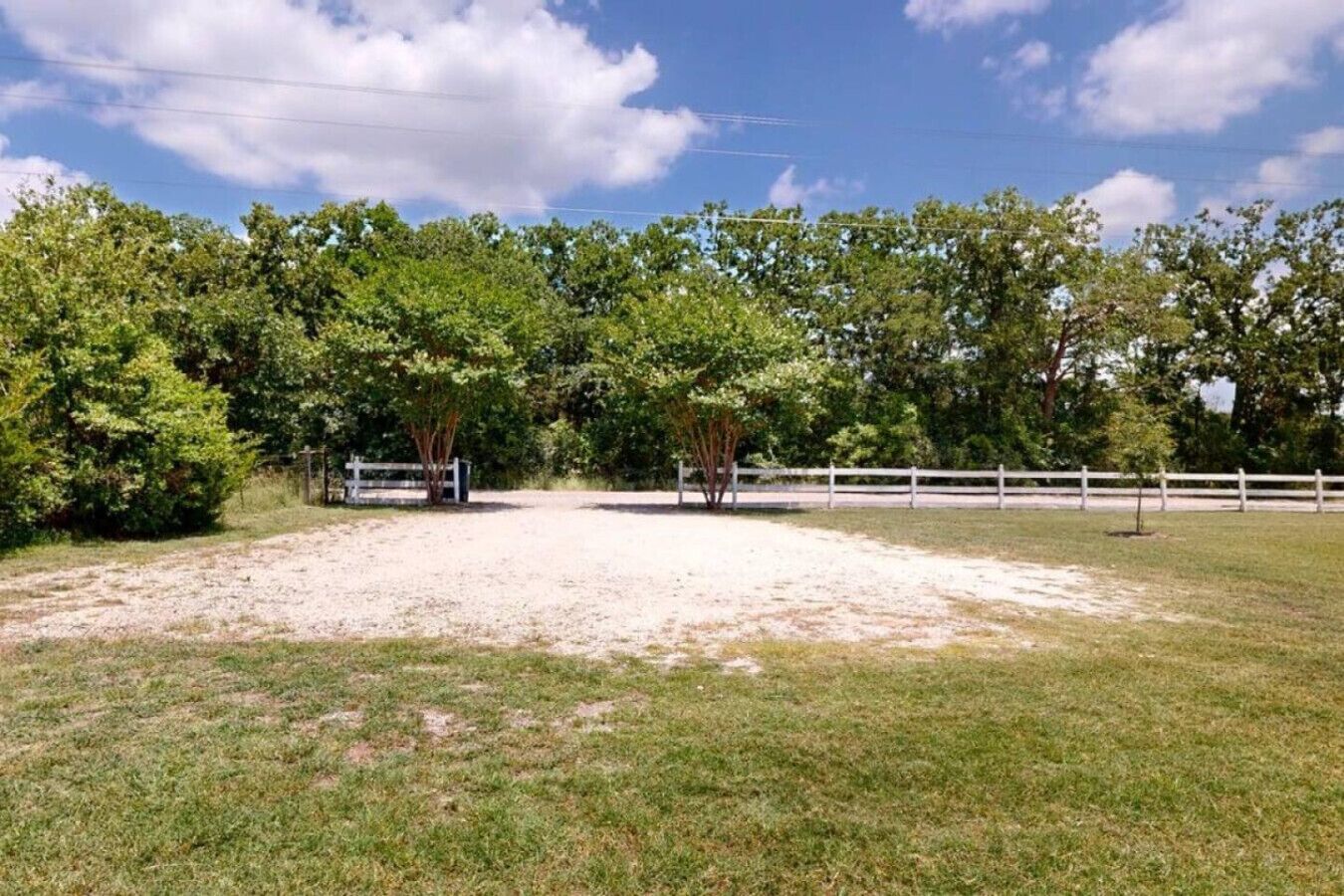 A fenced outdoor area with trees and a dirt path.