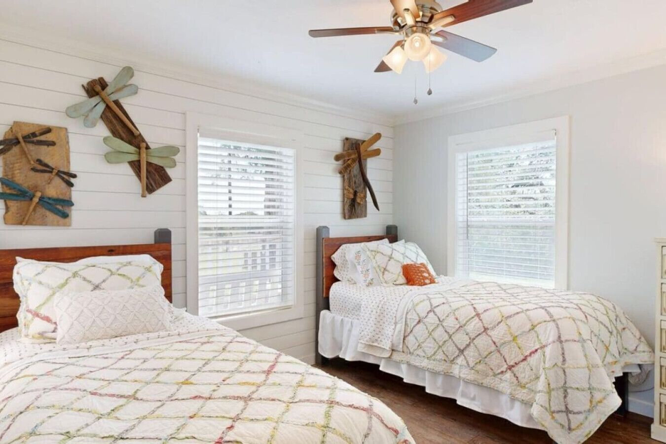 A bedroom with two beds, wooden headboards, and a ceiling fan.