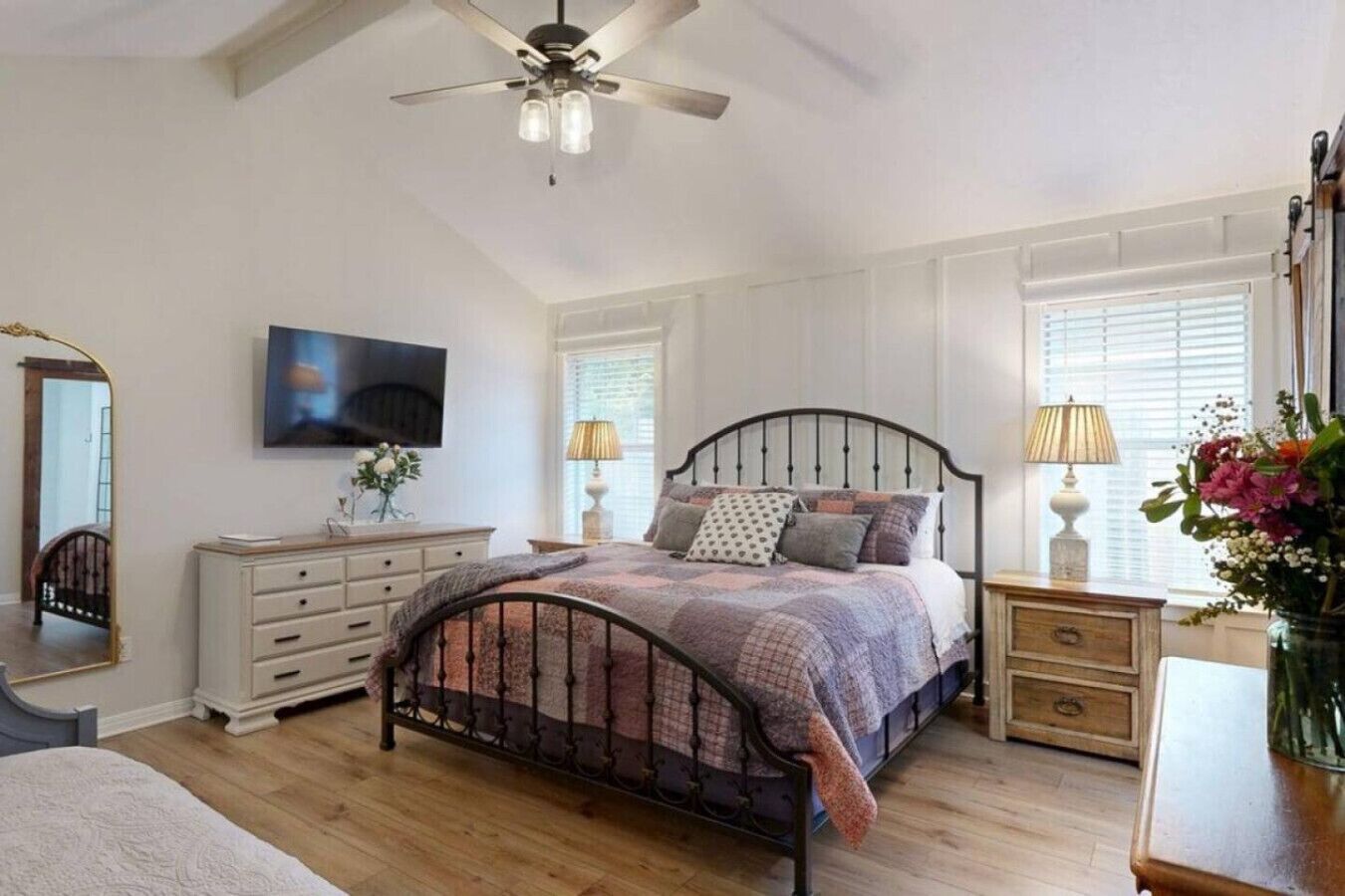 Un dormitorio con cama, cómoda, tocador y ventilador de techo.