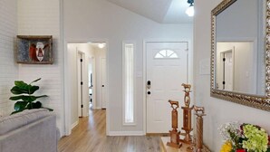 A hallway with a white door, a mirror, and a plant.